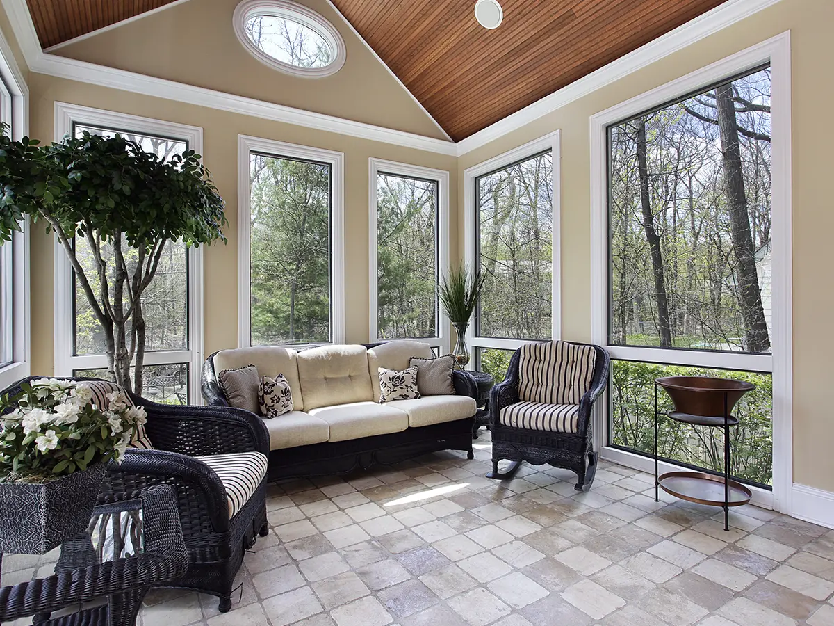 A sunroom with tile flooring and outdoor furniture
