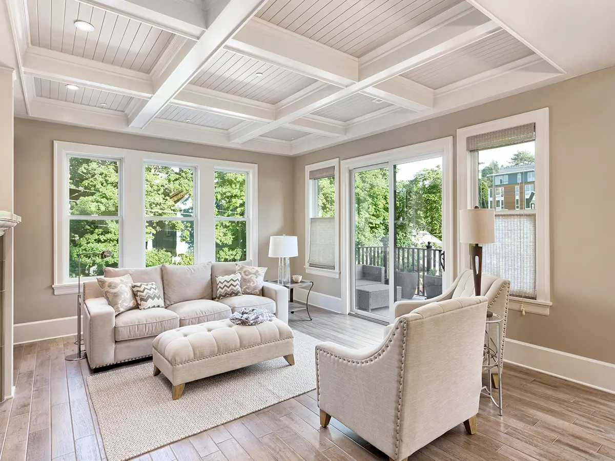 A sunroom with laminate flooring and a white couch and chairs