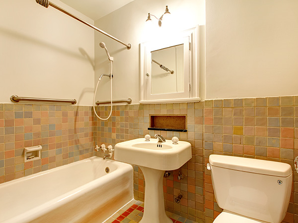 A dated bathroom with tile walls and floors and a tub and shower combo
