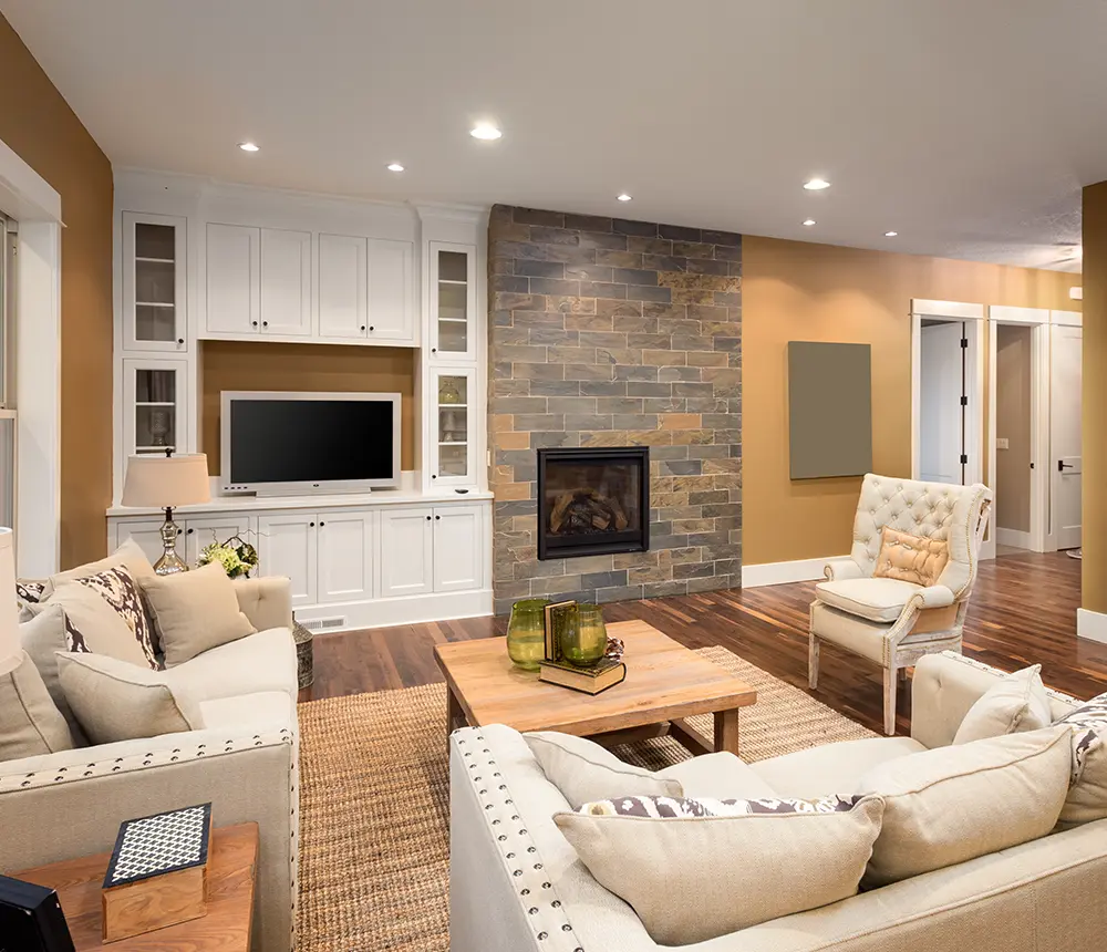 A living space with wood flooring, a fireplace, two white couches, and some cabinets