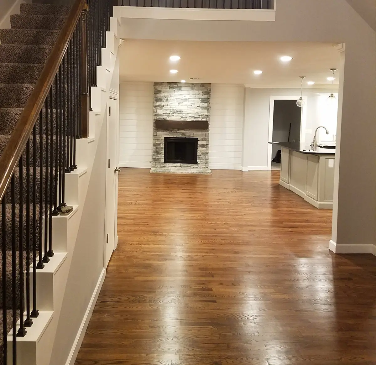 A basement with a fireplace, a kitchenette, and hardwood floors