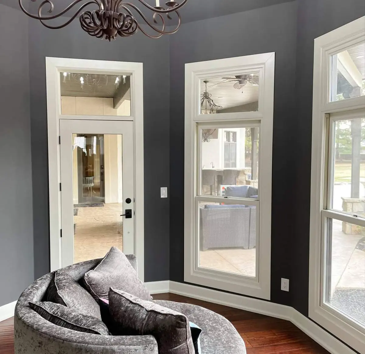 A sunroom with a gray chair and large windows