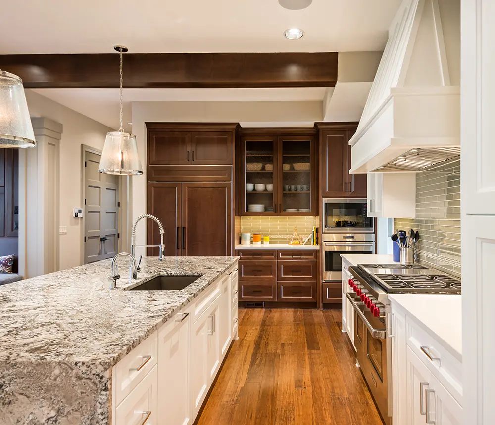 A kitchen with wood floors and an island with a granite waterfall countertop