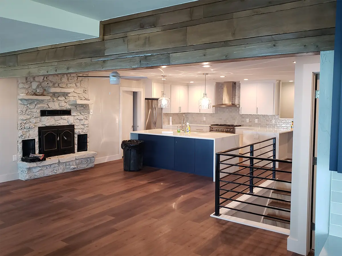 An open space kitchen with wood flooring and white kitchen cabinets with a blue island