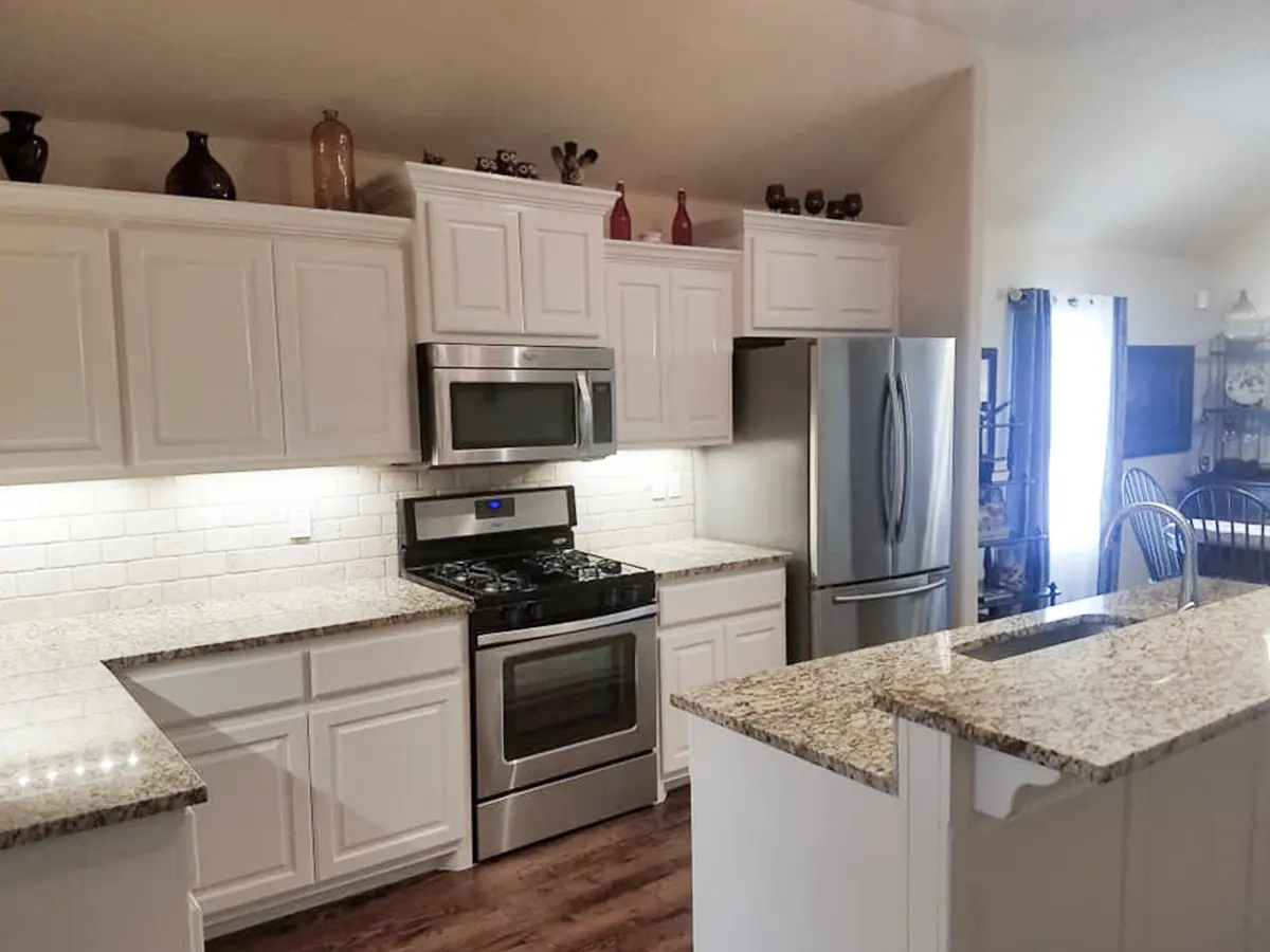 White kitchen cabinets without the pulls installed and granite countertops