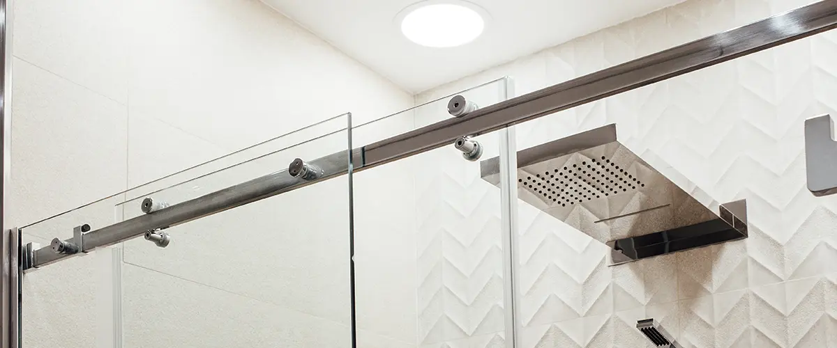 Metal structure of the upper fasteners and rollers for the sliding glass door in the shower view in white the interior
