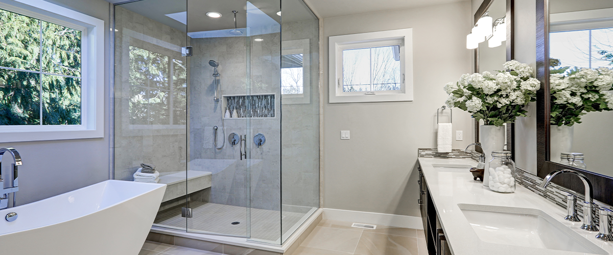 A spacious modern bathroom with a glass-enclosed shower, freestanding bathtub, and double vanity. The space is bright and elegant.