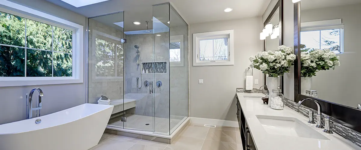 Luxurious bathroom remodeling in Sand Springs, with skylight, glass-enclosed shower, freestanding tub, double vanity, and elegant decor.